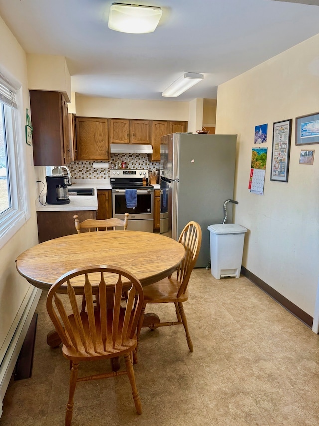 kitchen with under cabinet range hood, appliances with stainless steel finishes, light countertops, decorative backsplash, and baseboards