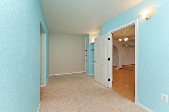 hall featuring carpet, arched walkways, and baseboards