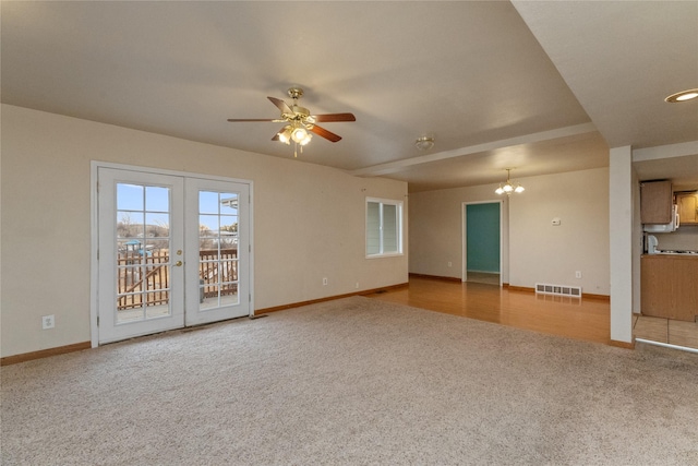 unfurnished living room with visible vents, baseboards, carpet flooring, ceiling fan with notable chandelier, and french doors