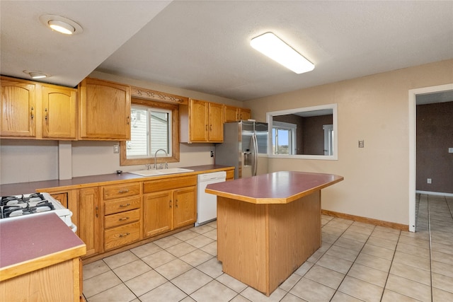 kitchen featuring a kitchen island, baseboards, light tile patterned floors, white appliances, and a sink