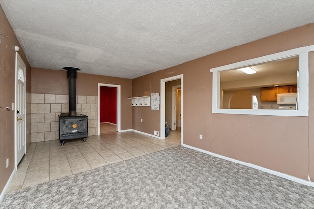 unfurnished living room with baseboards, carpet floors, a wood stove, tile patterned flooring, and a textured ceiling