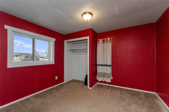 unfurnished bedroom with baseboards, a closet, carpet floors, and a textured ceiling