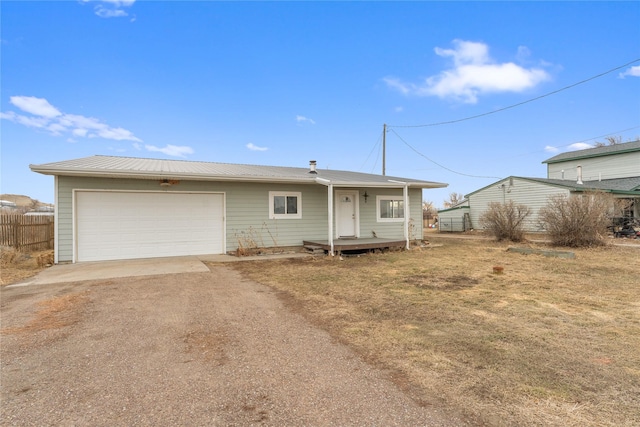 view of front of home featuring a garage, metal roof, dirt driveway, and fence