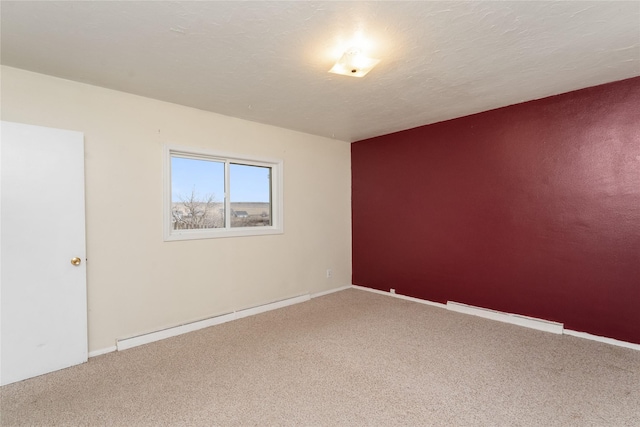 carpeted spare room featuring a baseboard heating unit, baseboards, and a textured ceiling