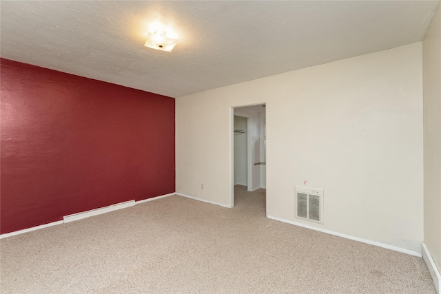 spare room with visible vents, carpet floors, a textured ceiling, and baseboards