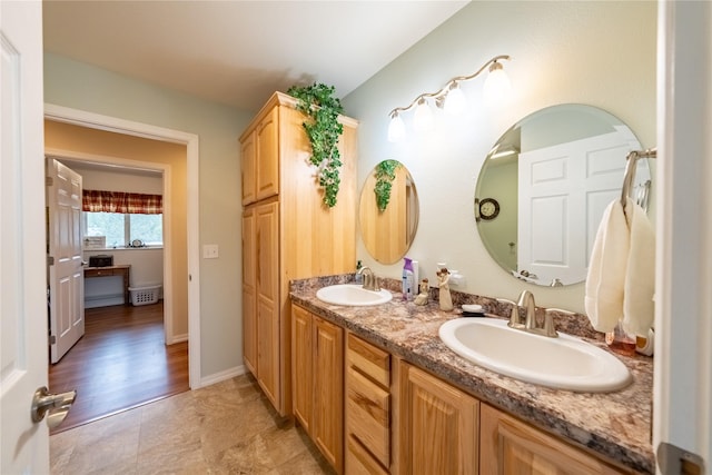 full bathroom with double vanity, baseboards, and a sink