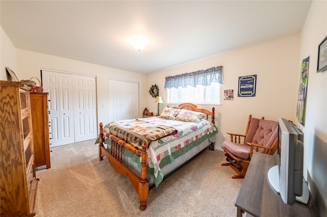 bedroom with light carpet and two closets