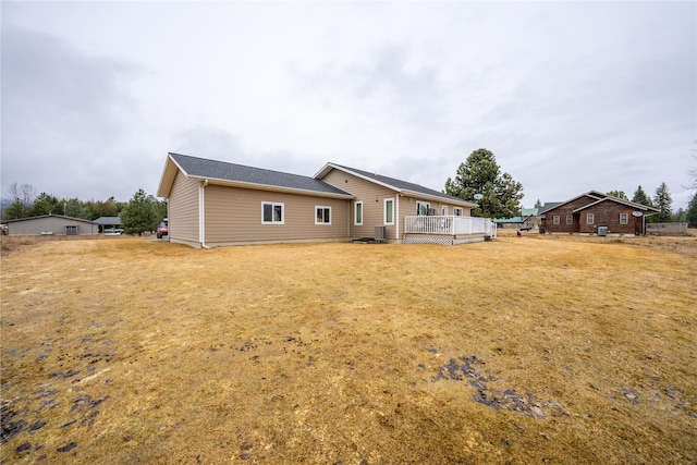 back of property with a wooden deck and a yard