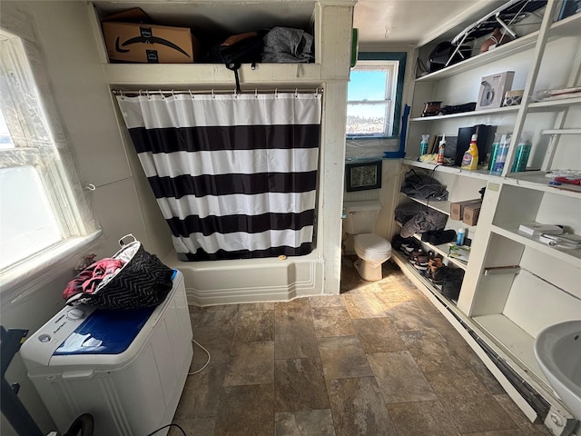 bathroom featuring shower / bath combination with curtain, toilet, and stone finish floor