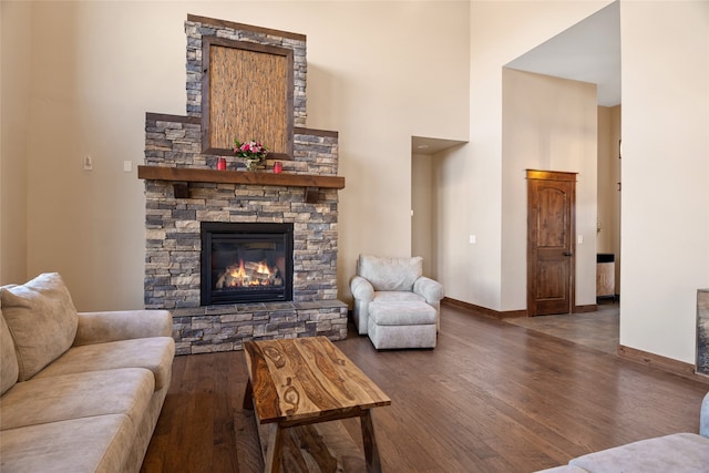 living room with a fireplace, a high ceiling, wood finished floors, and baseboards