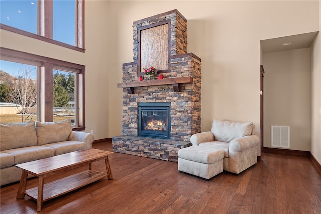 living area featuring visible vents, a high ceiling, wood finished floors, and a fireplace