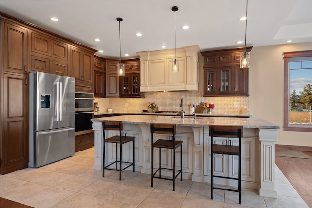 kitchen featuring light stone counters, backsplash, glass insert cabinets, and stainless steel refrigerator with ice dispenser