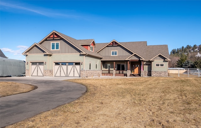 craftsman inspired home with fence, a porch, an attached garage, stone siding, and board and batten siding