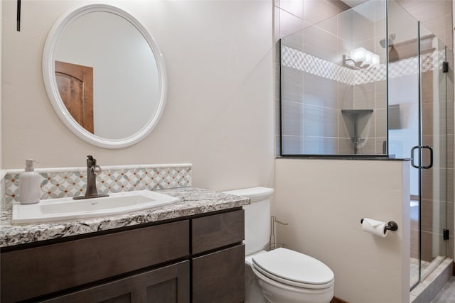 bathroom featuring vanity, a shower stall, and toilet