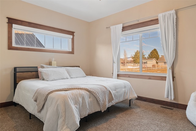 carpeted bedroom featuring visible vents, multiple windows, and baseboards