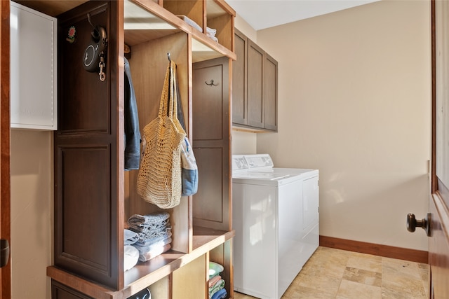 washroom featuring washer and clothes dryer, cabinet space, and baseboards