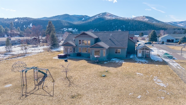 view of front of home featuring a mountain view, an outdoor structure, roof with shingles, and a fenced backyard