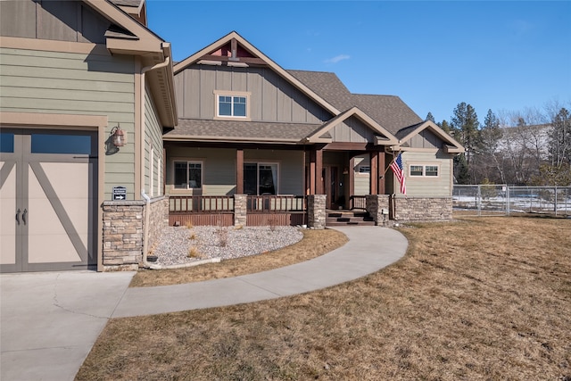 craftsman-style home with a porch, board and batten siding, stone siding, and roof with shingles