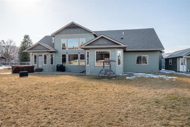 back of property featuring board and batten siding, entry steps, roof with shingles, a lawn, and a patio