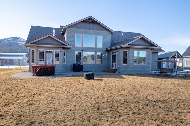 back of house featuring a lawn, entry steps, a hot tub, board and batten siding, and a patio area