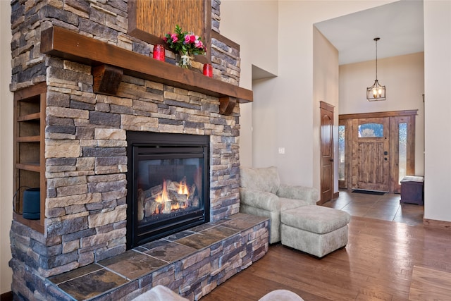 living area with a towering ceiling, wood finished floors, and a fireplace