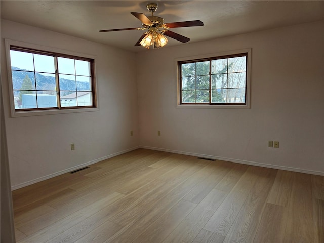 unfurnished room with visible vents, plenty of natural light, light wood-style flooring, and baseboards