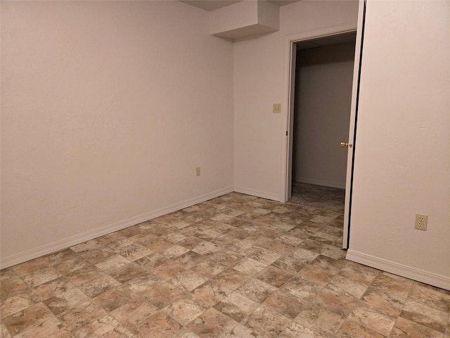 unfurnished room featuring baseboards and stone finish flooring