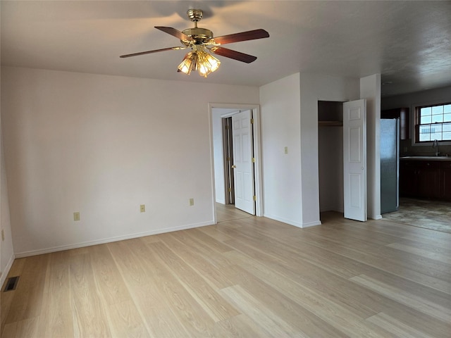 spare room featuring a sink, visible vents, light wood-style flooring, and a ceiling fan