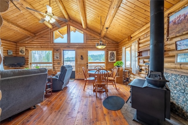 dining room featuring beamed ceiling, high vaulted ceiling, a wood stove, and wood-type flooring