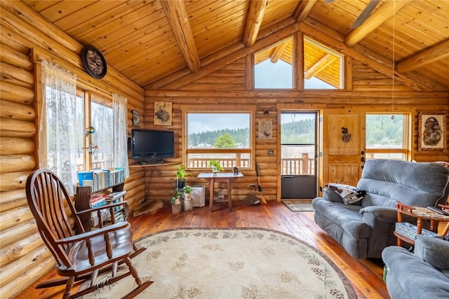 living area featuring beam ceiling, a healthy amount of sunlight, and hardwood / wood-style flooring