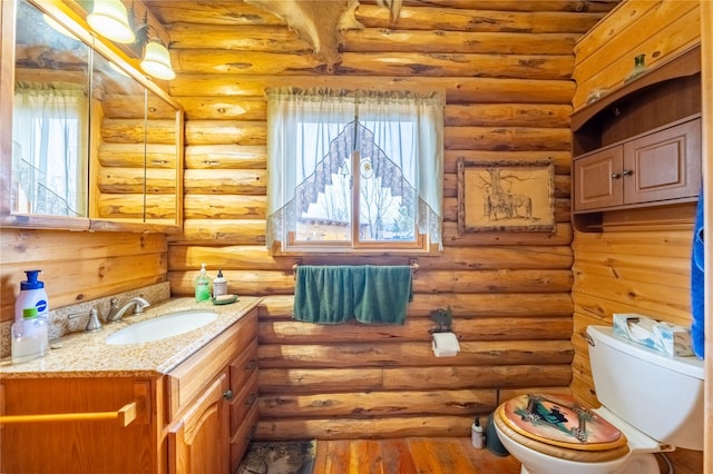 half bath with log walls, toilet, wood finished floors, and vanity