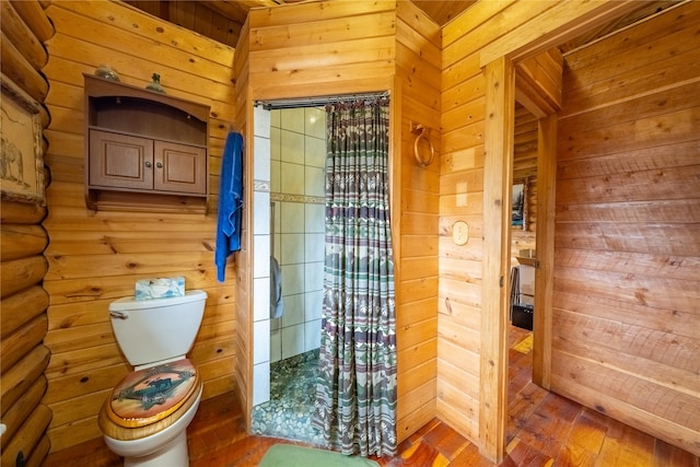 bathroom featuring wooden walls, toilet, a shower with curtain, and wood finished floors