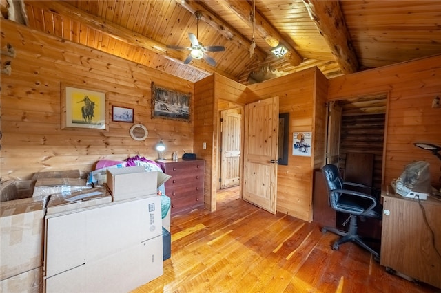 office space with wood walls, lofted ceiling with beams, wooden ceiling, light wood-style floors, and a ceiling fan