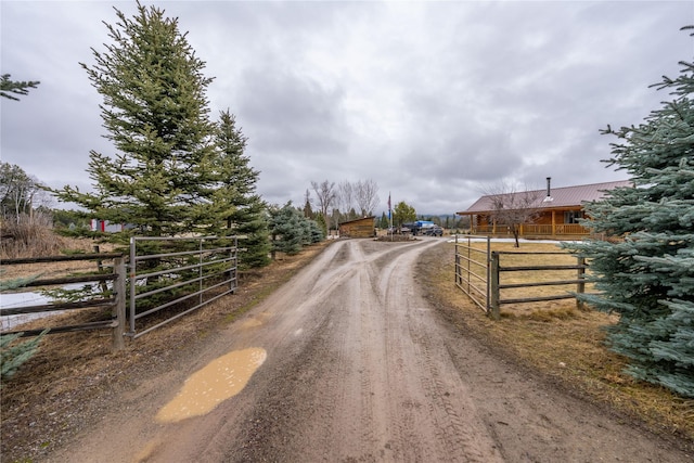 view of road featuring dirt driveway and a gated entry