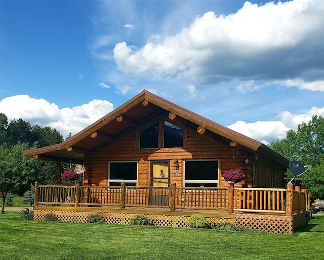 cabin with log siding, a deck, and a front lawn