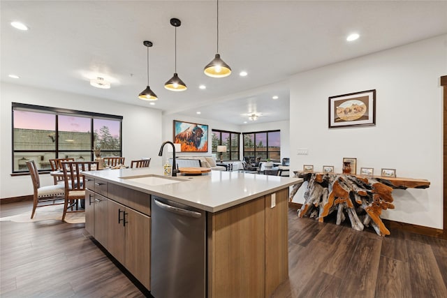 kitchen with a center island with sink, dark wood finished floors, a sink, light countertops, and dishwasher