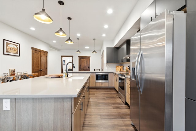 kitchen featuring wood finished floors, recessed lighting, a sink, light countertops, and appliances with stainless steel finishes