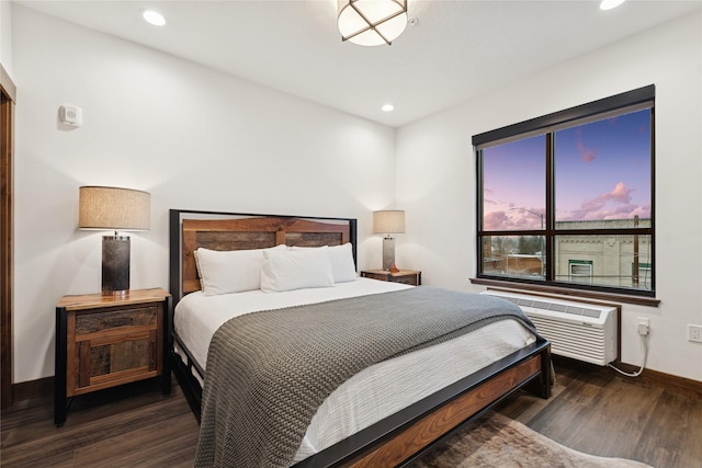 bedroom featuring dark wood finished floors, recessed lighting, an AC wall unit, and baseboards