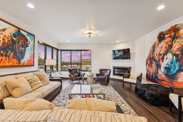 living room with a glass covered fireplace, recessed lighting, wood finished floors, and a textured ceiling