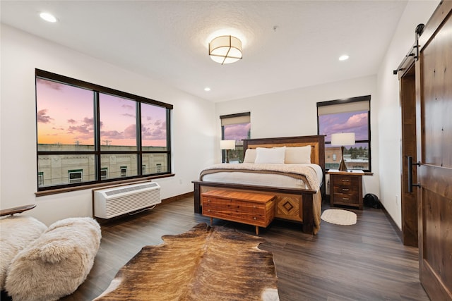 bedroom with a wall mounted AC, wood finished floors, recessed lighting, a barn door, and baseboards