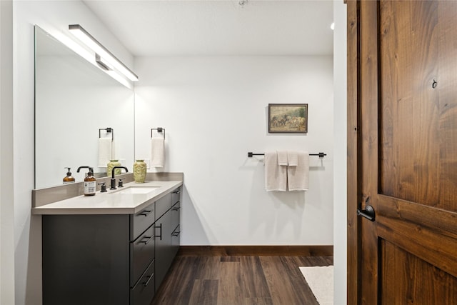 bathroom with baseboards, wood finished floors, and vanity