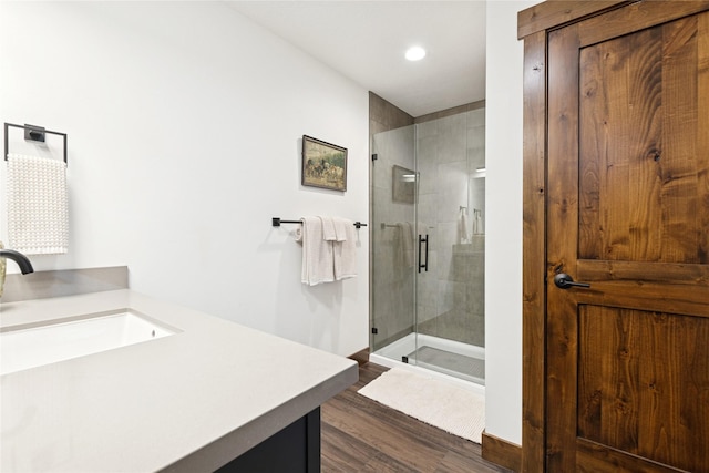 full bath with vanity, a shower stall, wood finished floors, and baseboards