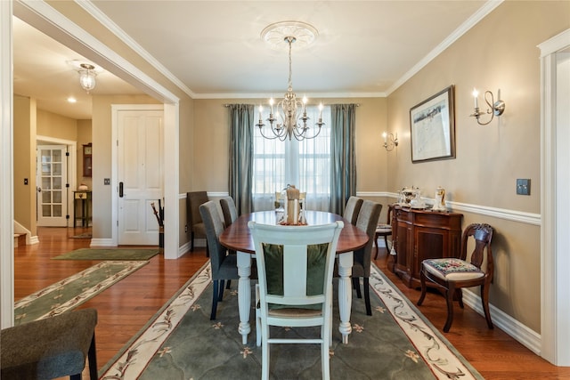 dining room featuring a notable chandelier, crown molding, baseboards, and wood finished floors