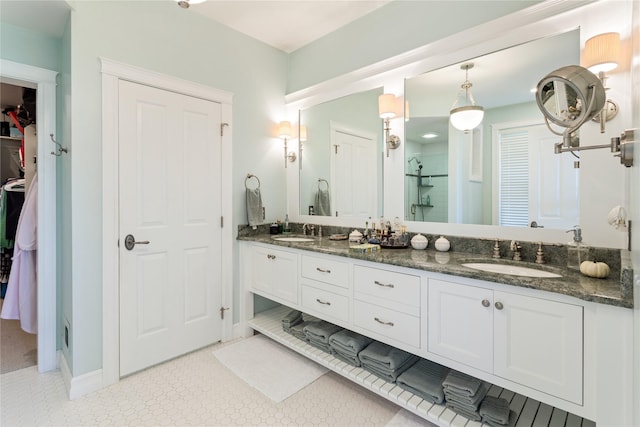 full bathroom with a sink, a walk in closet, a shower with door, and double vanity