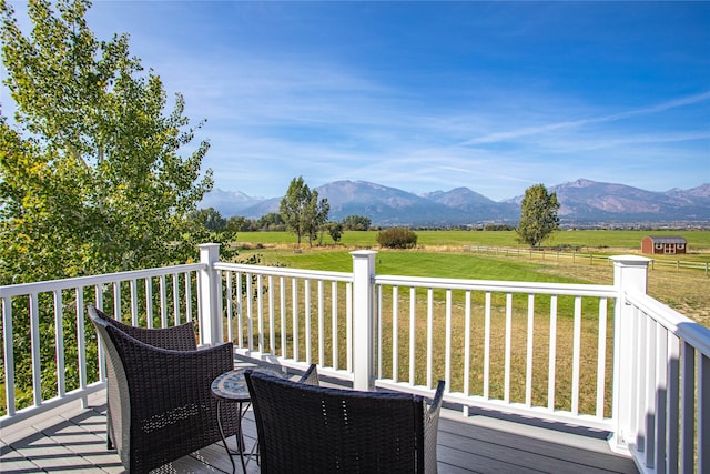 deck with a mountain view, a lawn, and a rural view