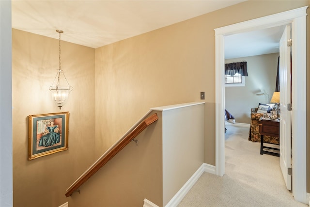 stairway with baseboards, a chandelier, and carpet flooring