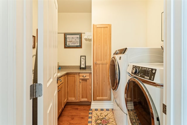 laundry area featuring cabinet space, independent washer and dryer, and wood finished floors