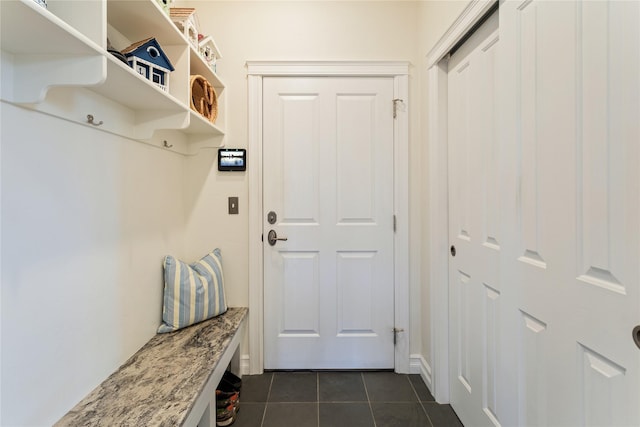 mudroom with dark tile patterned floors