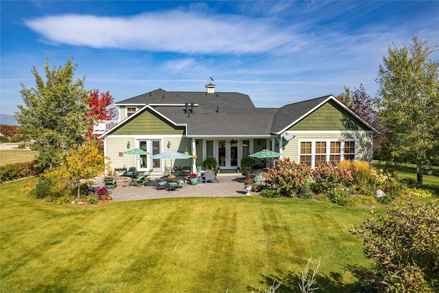 rear view of property with a patio area, a yard, french doors, and a shingled roof