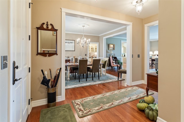 dining area featuring baseboards, a notable chandelier, wood finished floors, and crown molding